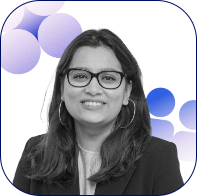 A professional headshot of Manasi wearing black frame glasses and a black blazer, smiling.
